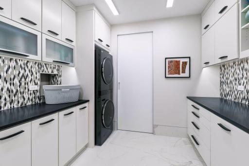 This spacious laundry room offers abundant cabinetry, generous counter space, and a dedicated storage room just beyond