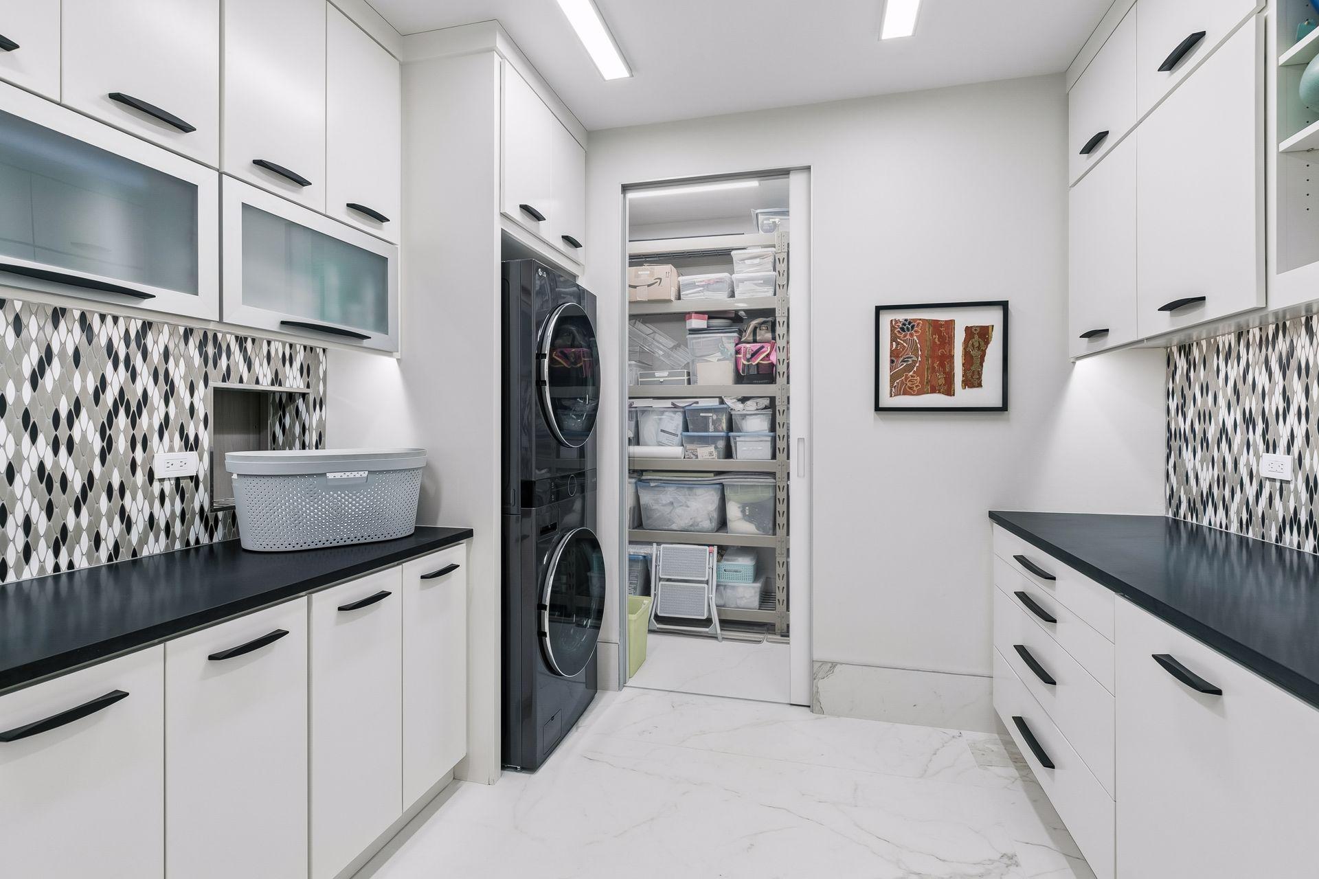 Features extensive built-in storage, sleek countertops, and a convenient pocket door connecting directly to the primary walk-in closet for effortless laundry drop-off.
