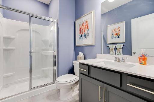 The main level bathroom offers a walk-in shower and oversized vanity. Photo of model home, colors and finished will vary.