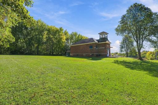 The property expands into the woods, with the front half mostly grass/building, back half trees.
