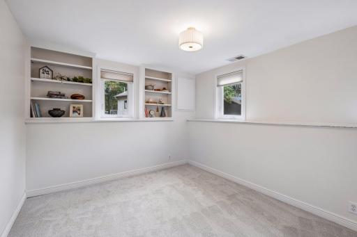 Fourth bedroom on lower level has built-in bookshelves and windows which offer plenty of natural light.
