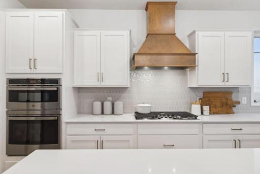 The kitchen features a double oven, gas cook top, stylish vent hood and quality stainless appliances.