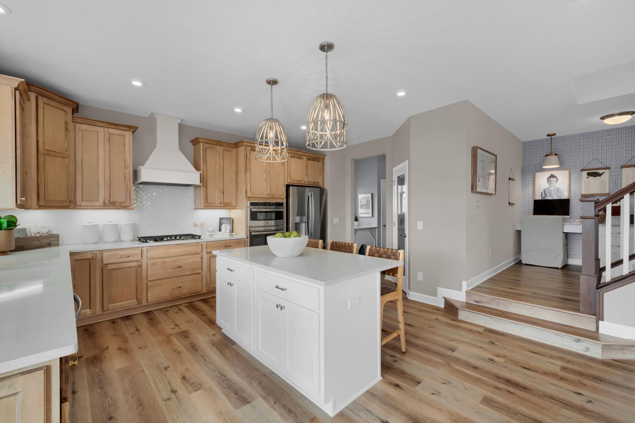 A bright and luxurious kitchen is the centerpiece of this home with stainless appliances, quartz countertops and lots of natural light while stylish pendant lights add a modern refined touch. (model photo)