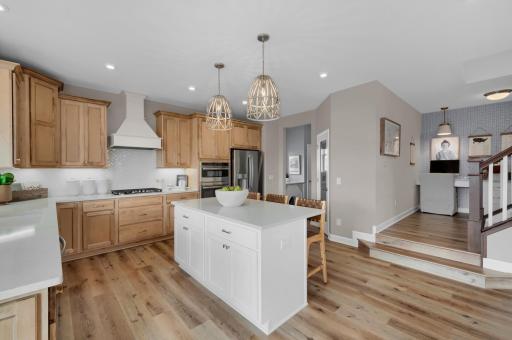 A bright and luxurious kitchen is the centerpiece of this home with stainless appliances, quartz countertops and lots of natural light while stylish pendant lights add a modern refined touch. (model photo)