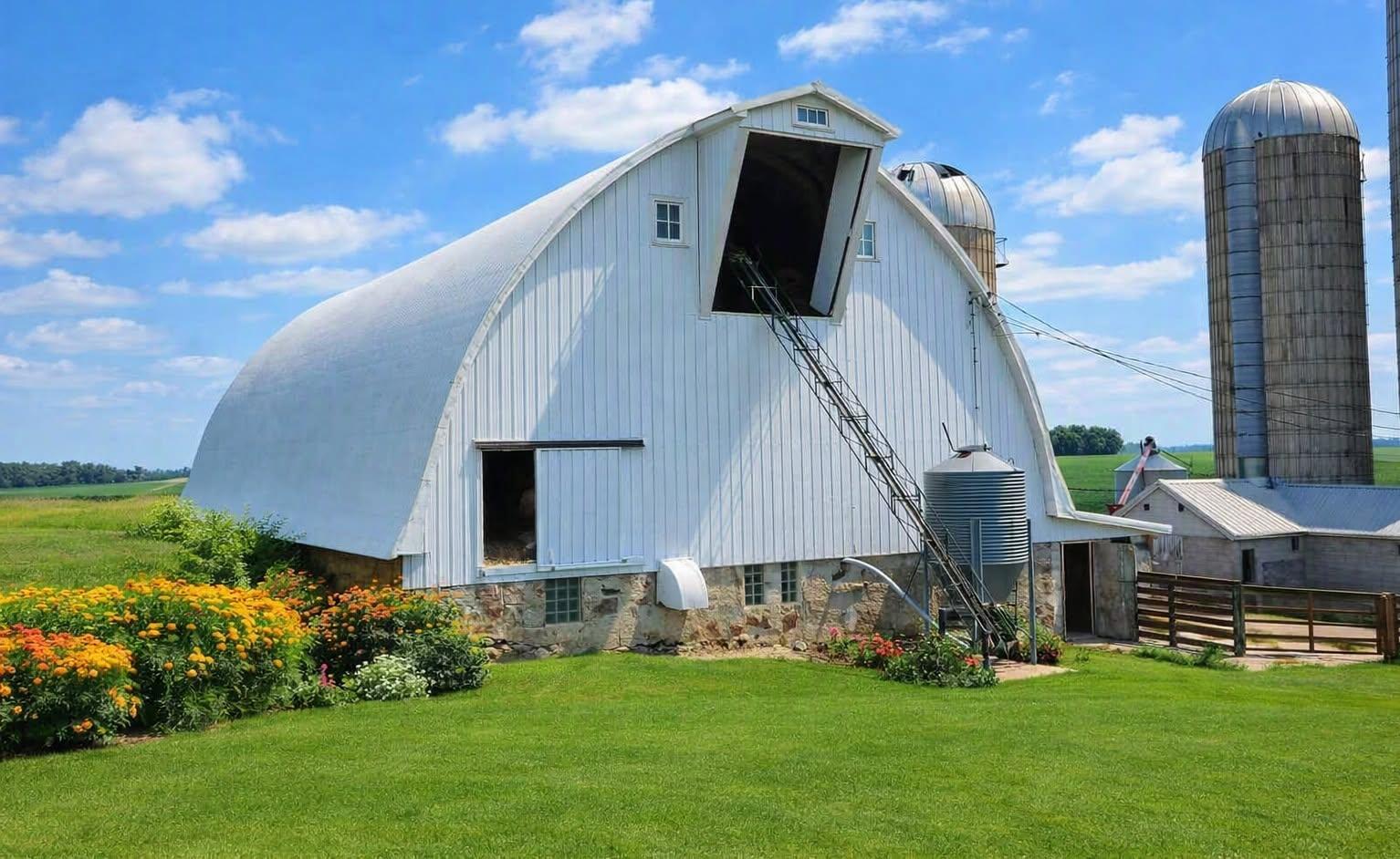 large barn set up for livestock on the main level and hay in the upper level