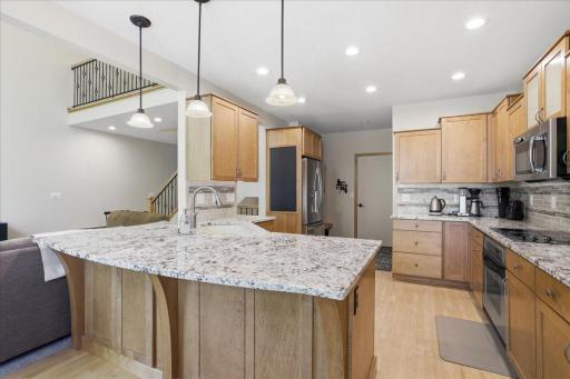 High-end kitchen design, chefs kiss, elevated appliances, cupboards, granite, island, eat-in kitchen, maple wood floors. Ample storage.