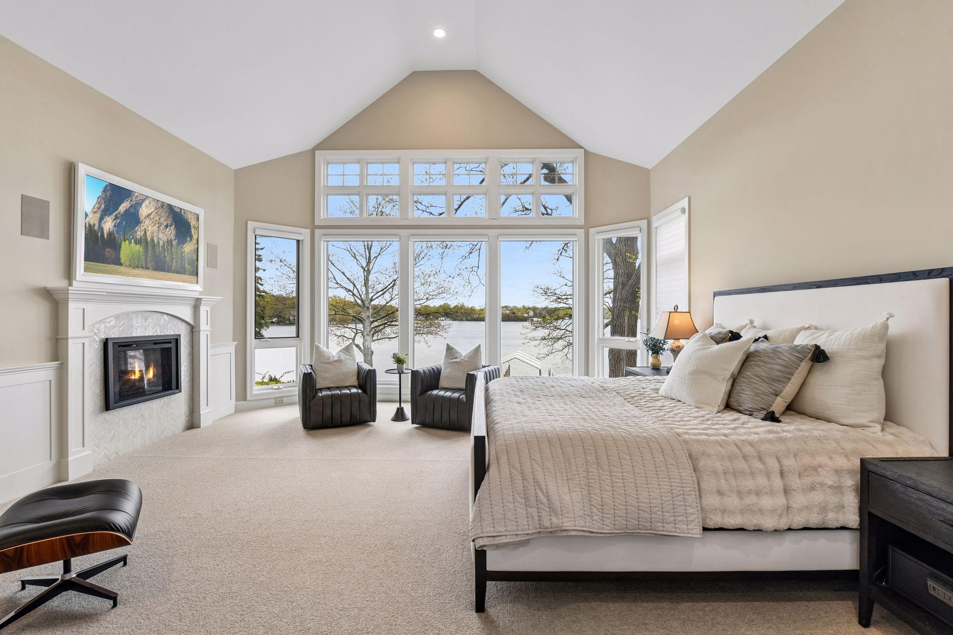 The main level primary suite is a serene escape featuring a gas fireplace, vaulted ceilings, automatic blinds, and renovated spa-like bathroom with sweeping water views.