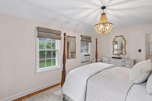 Bedroom #1 with warm hardwood floors, and a tranquil view of the private backyard.