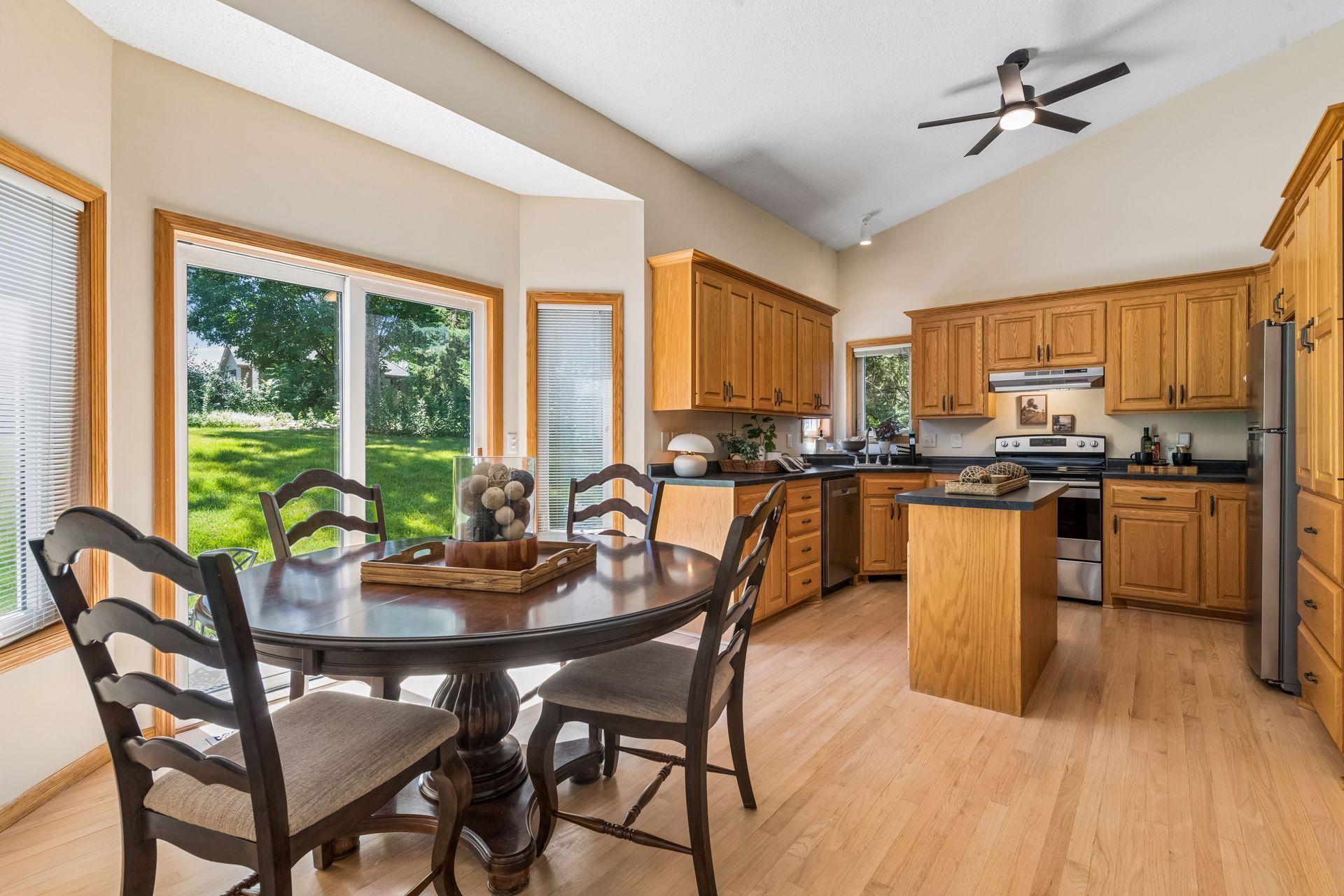 Vaulted ceilings and expansive windows fill this open-concept space with natural light. The effortless flow between the kitchen, dining area, and family room is ideal for gathering.