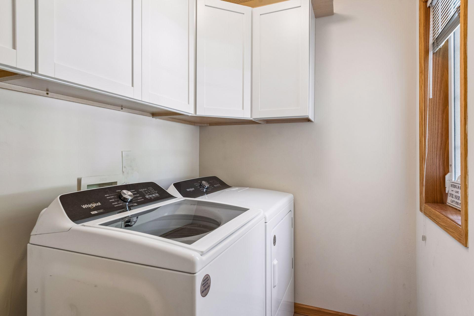 The main floor laundry room offers upper storage cabinets, a window for natural light, and space to add a utility sink, creating a practical and functional workspace.