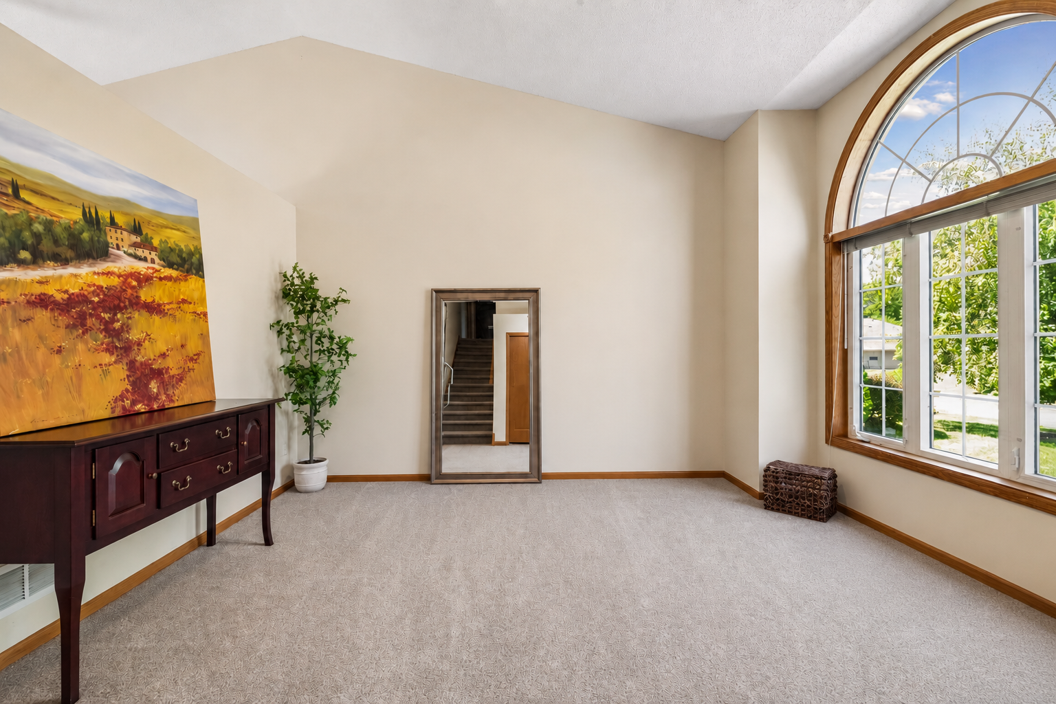 The living room features vaulted ceilings, a dramatic picture window with an arched transom, and new carpet and pad. This photo has been digitally edited to remove personal property, allowing you to envision the space as your own.