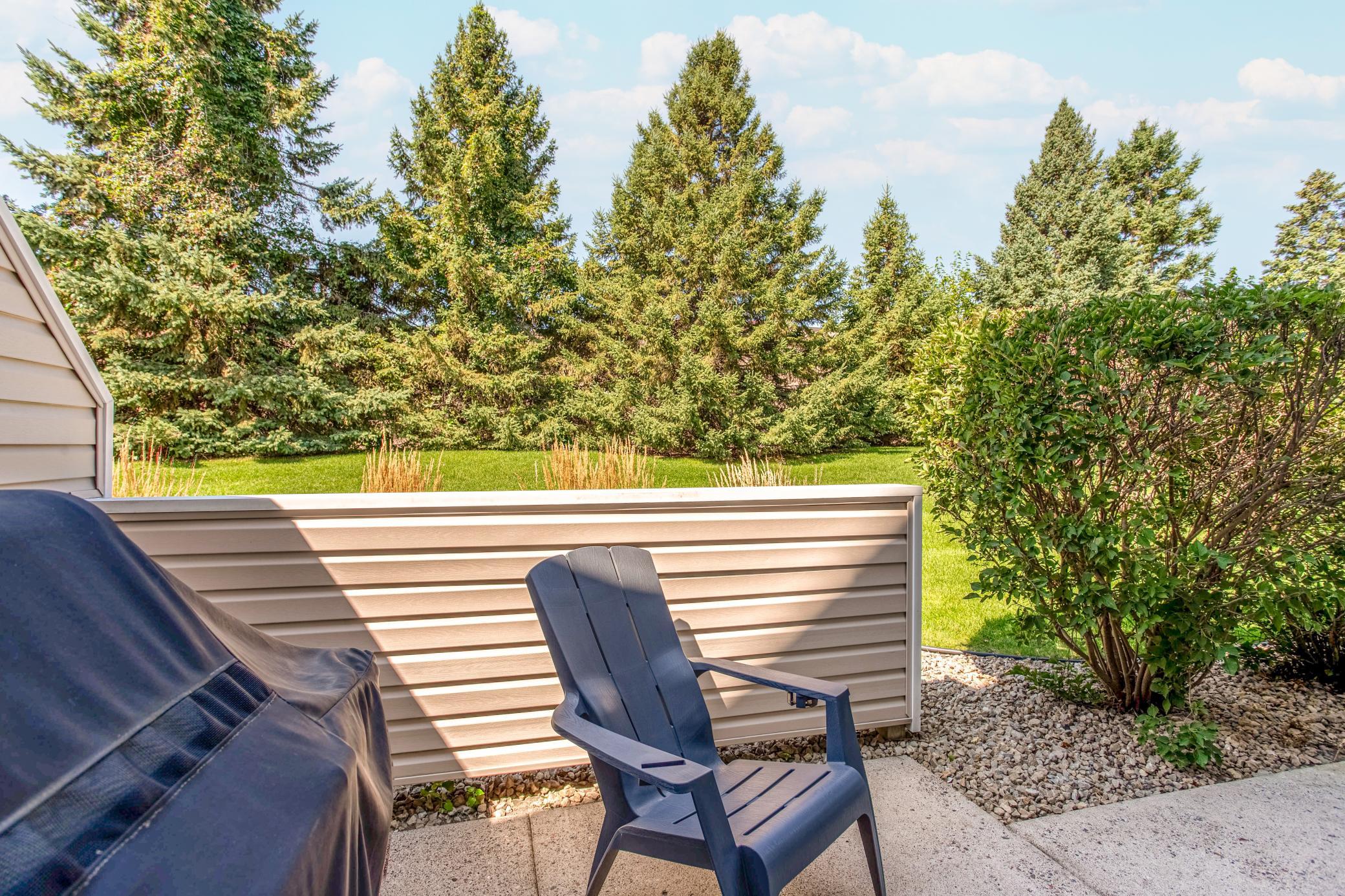 Peaceful patio setting with a beautiful green backdrop and mature trees creating added privacy.