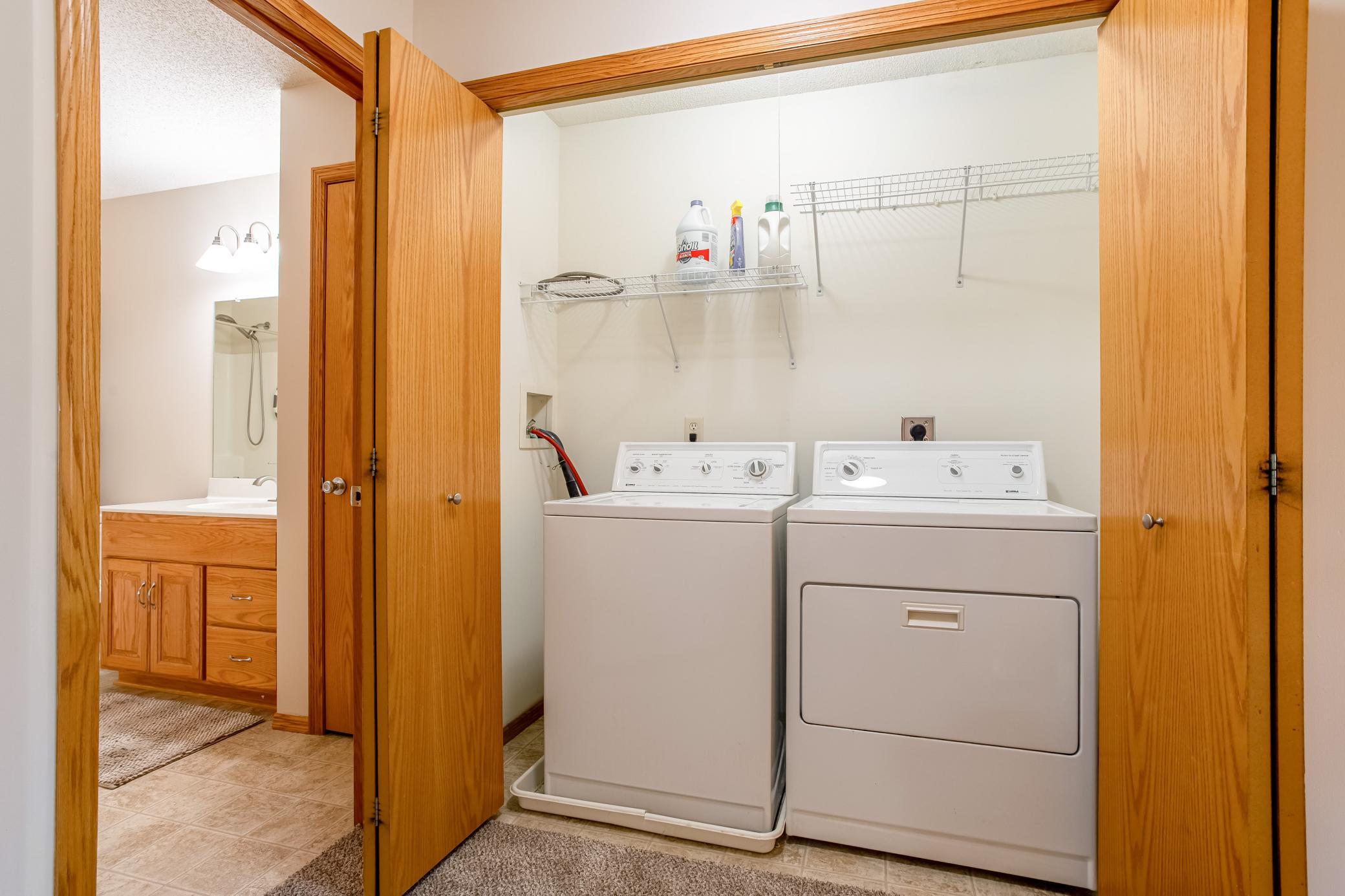 Conveniently located laundry area with washer and dryer, shelving for supplies, and easy access near the bedrooms.