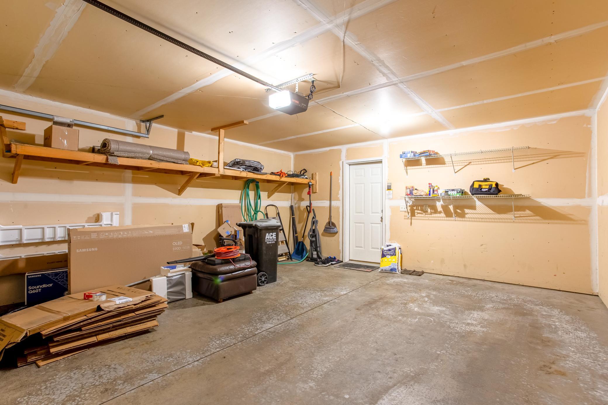 Spacious attached two-car garage offers built-in shelving and plenty of room for parking and additional storage.