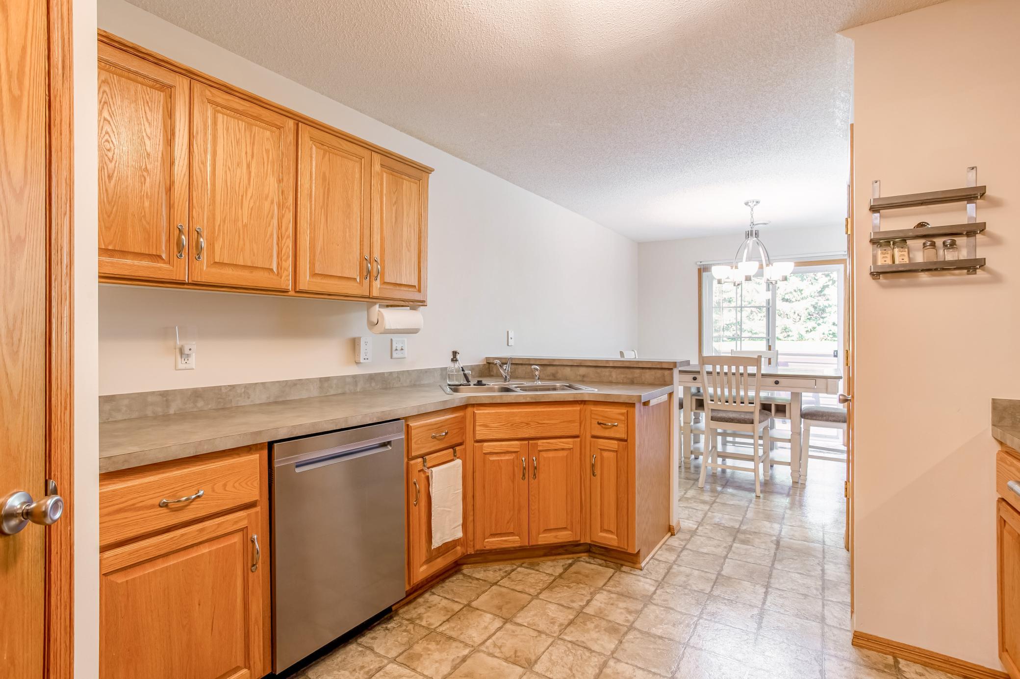 Functional kitchen layout offers generous cabinet and counter space, stainless-steel dishwasher, and an easy connection to the dining area.