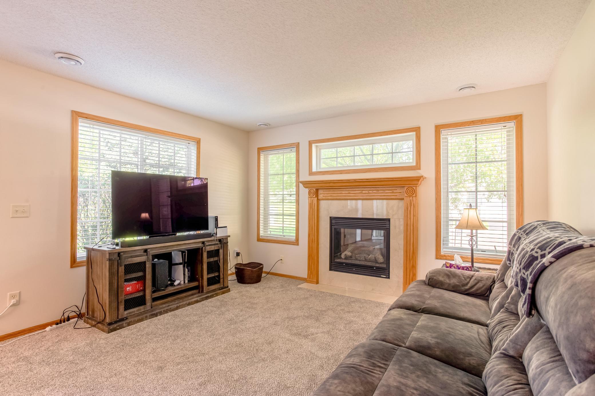 Bright and inviting living room featuring a gas fireplace, abundant windows, and comfortable everyday living space.