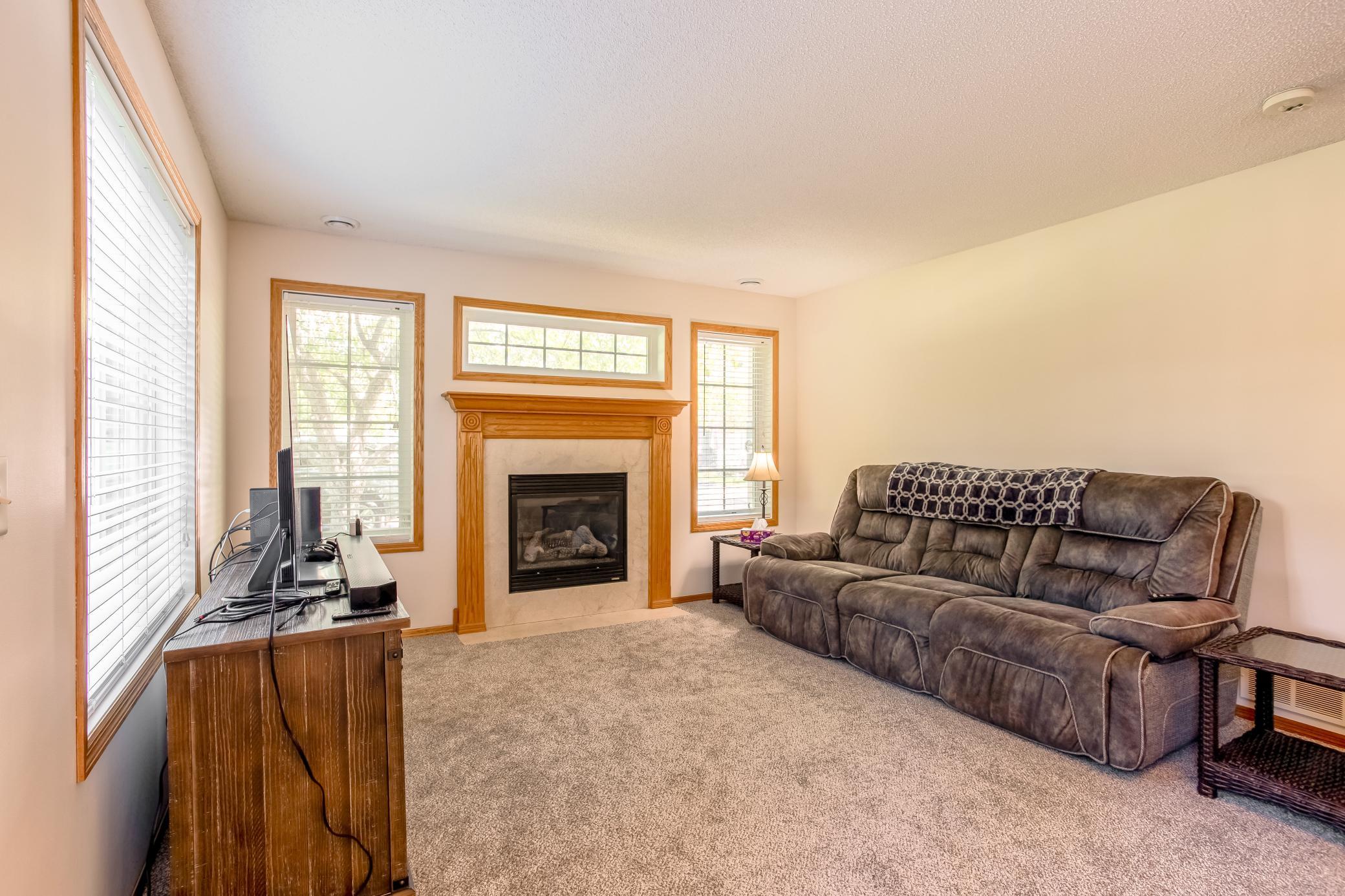 Spacious living room highlighted by a cozy gas fireplace and multiple windows that fill the space with natural light.