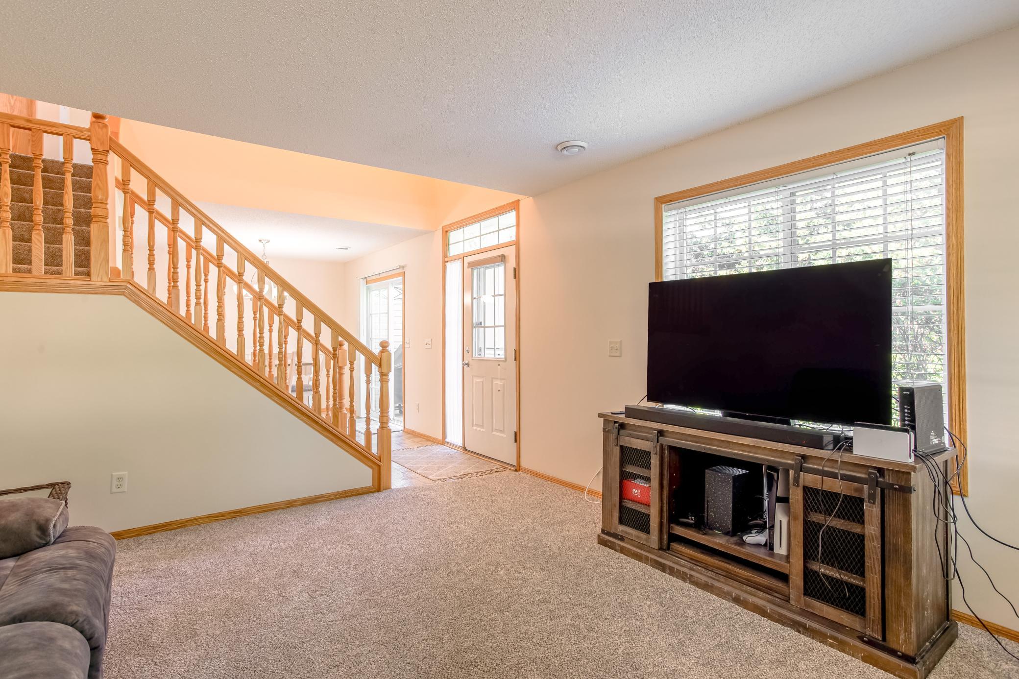 Open living area flows toward the front entry and staircase, with a large picture window bringing in plenty of natural light.
