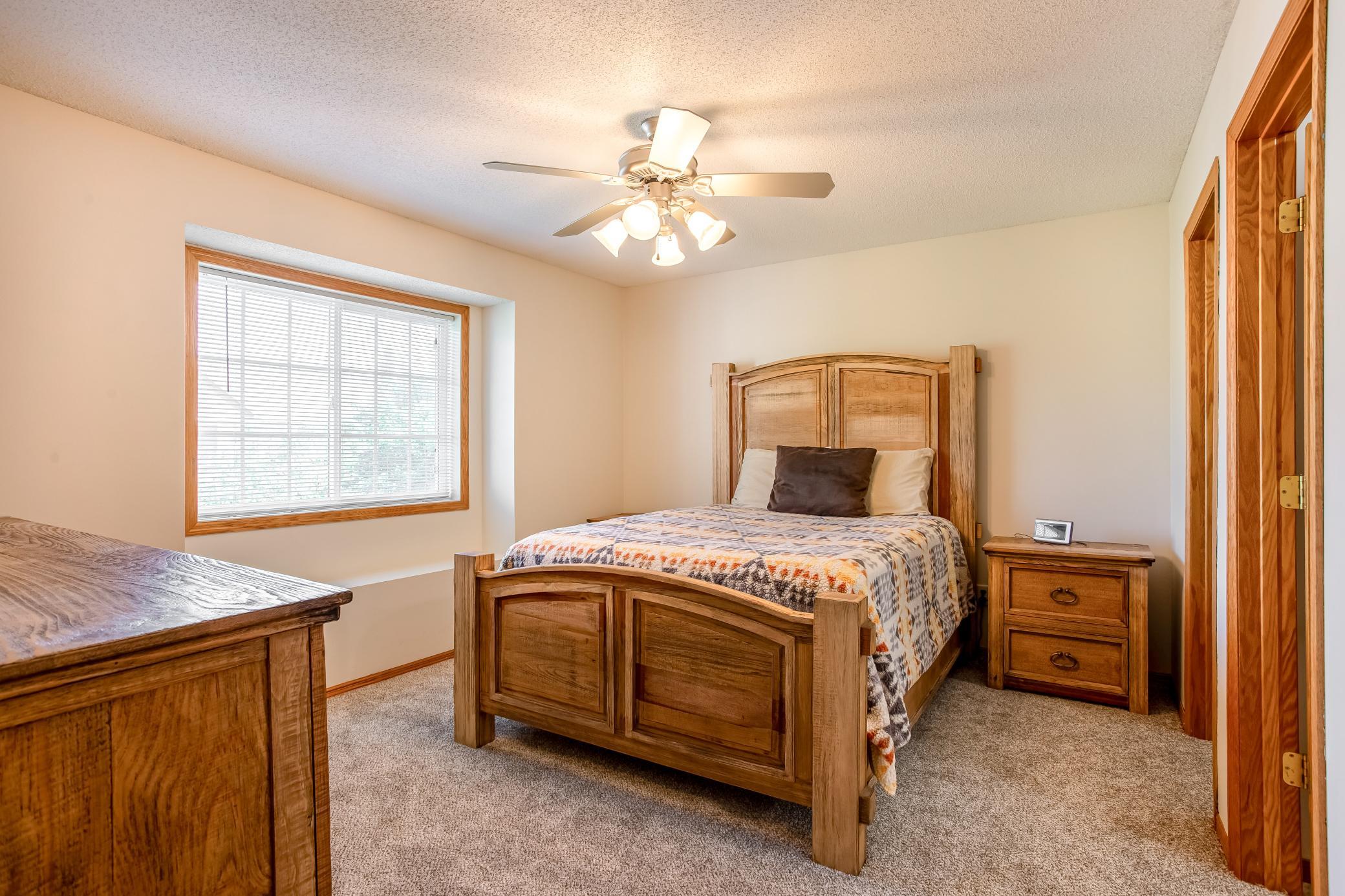 Inviting primary bedroom with abundant natural light, ceiling fan, and brand-new carpet for a fresh, comfortable feel.