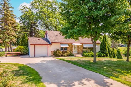 Gorgeous curb appeal welcomes you home, with mature trees, established landscaping, and an attached garage creating an inviting first impression.