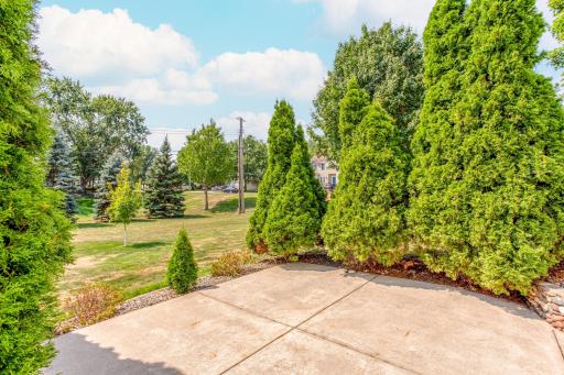 A closer look at the patio showcases its privacy, established landscaping, and towering Arborvitae treesâa welcoming spot to unwind and enjoy the park-like surroundings.
