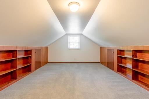Versatile upper-level bedroom features a charming sloped ceiling, built-in shelving, and convenient integrated storage.