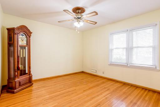Main-level bedroom features beautiful hardwood floors, a ceiling fan, and multiple windows providing abundant natural light.