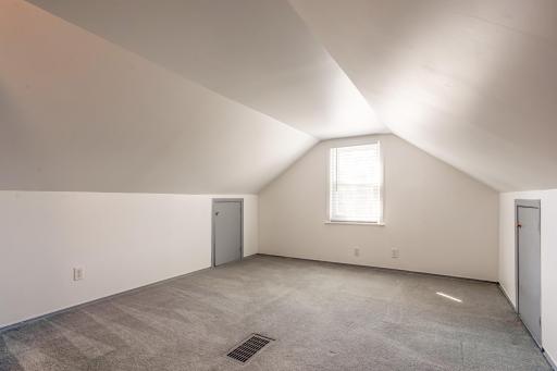 Spacious upper-level bedroom features built-in storage, neutral finishes, new carpeting, and natural light.