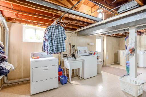 Lower-level laundry area provides ample workspace with utility connections and natural light from a window.