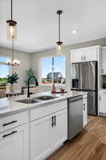 PHOTO OF A DIFFERENT HOME WITH SIMILAR PLAN & FINISHES. Kitchen center island features a trash/recycling base cabinet pullout conveniently located near the sink.