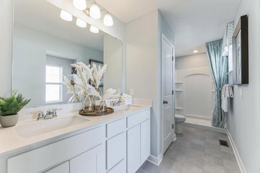 The primary bath features quartz countertops and dual sinks - making getting ready on those hectic mornings that much easier! And oversized stand-in shower! Photo of model, colors and options may vary.