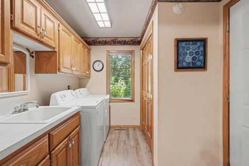 The main floor laundry room features: laminate flooring, a utility sink, overhead cabinets and another coat closet for lots of added storage. The Amana washer & dryer were replaced in 2025. This home also included an *unmonitored* security system.