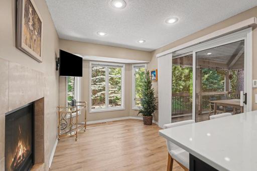 This informal dining area features: an updated fireplace (2017) w/ceramic tile surround, laminate flooring, a bay window overlooking the private backyard, recessed lights, and a sliding glass door that leads to the screened porch. The TV is included.