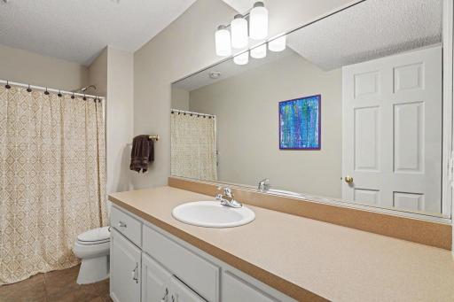 The lower level 3/4 bathroom features: painted walls & trim (2024), ceramic tile flooring; a spacious, comfort height vanity; updated Kohler toilet; shower stall with fiberglass surround; updated light fixture; and an exhaust fan.