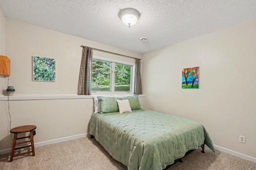 The 3rd bedroom features: updated carpet (2019), painted walls & trim (2024), in-ground sprinkler control panel, and a north-facing window overlooking the private backyard. There are 2 storage rooms across the hall - both include built-in shelving.