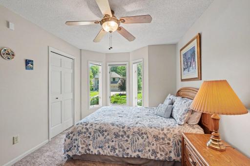 The 2nd main floor bedroom features: updated carpet (2019), painted walls & trim (2024), a ceiling fan, and a south-facing bay window - overlooking the front yard.