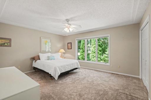 The main floor, primary bedroom offers 2 closets. It also features: a race track ceiling with fan, updated carpet (2019), painted walls & trim (2024), and a large north-facing window - overlooking the private backyard.