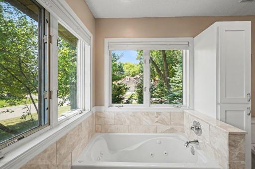 The primary bathroom offers: a jetted tub w/marble surround & recessed lights; & a convenient linen cabinet. The south & west-facing windows provide lots of natural light - both of them have shades that open from the top & bottom for custom privacy.