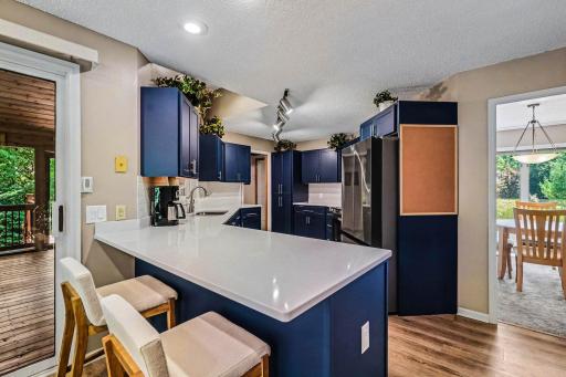 The dining room leads into the gorgeously, updated kitchen (2021). Updates include: laminate flooring, painted cabinets (with new fronts, and soft close doors & drawers), Quartz countertops, and recessed lights over the breakfast bar.