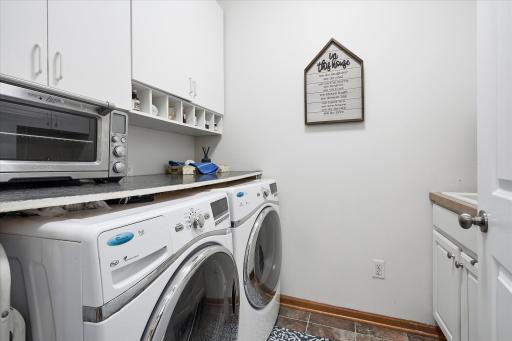 The main level laundry features a sink, included front loading laundry machines and extra folding & storage space.