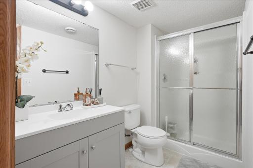 The lower level 3/4 bath features a new vanity, tile flooring and a walk-in shower.