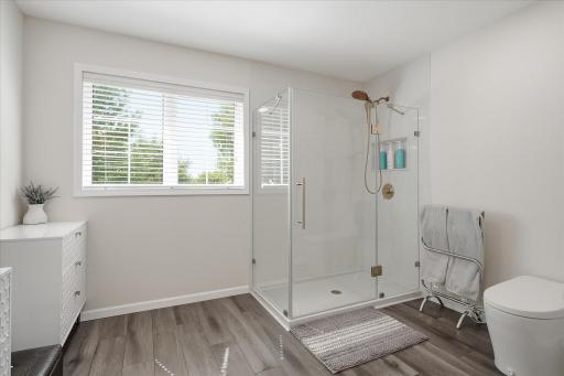 The walk-in shower features a floor to ceiling surround with frameless glass and modern gold fixtures.