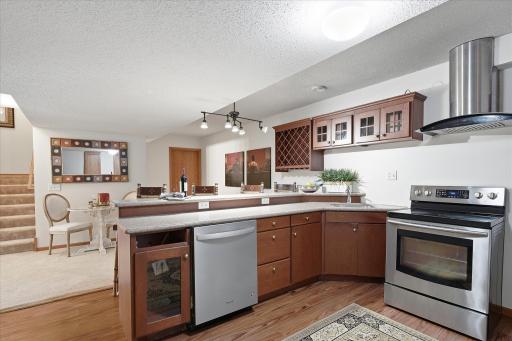 There is a sink, a dishwasher, an electric range with a vent hood and a fridge too!