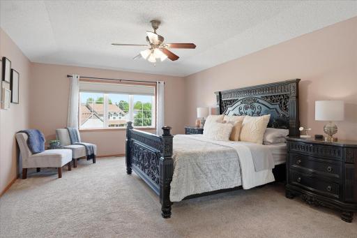 The primary bedroom features modern & neutral carpet & paint, PLENTY of space for a king bed, a tray-vault ceiling and a ceiling fan/light combo.