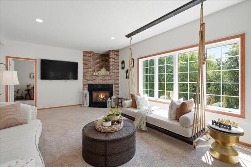 The family room features bright, modern & neutral carpet & paint and a brick surround gas fireplace.