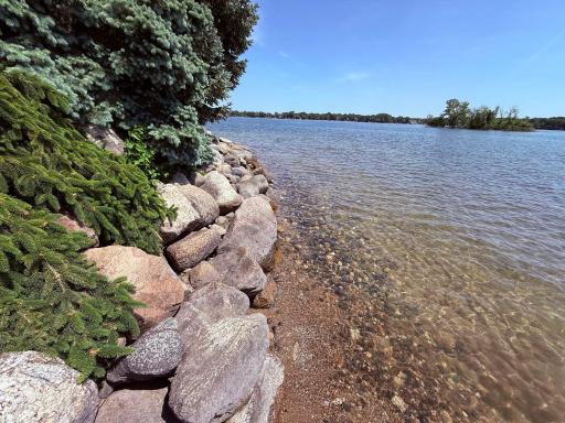 Sandy shoreline with large rip rap boulders
