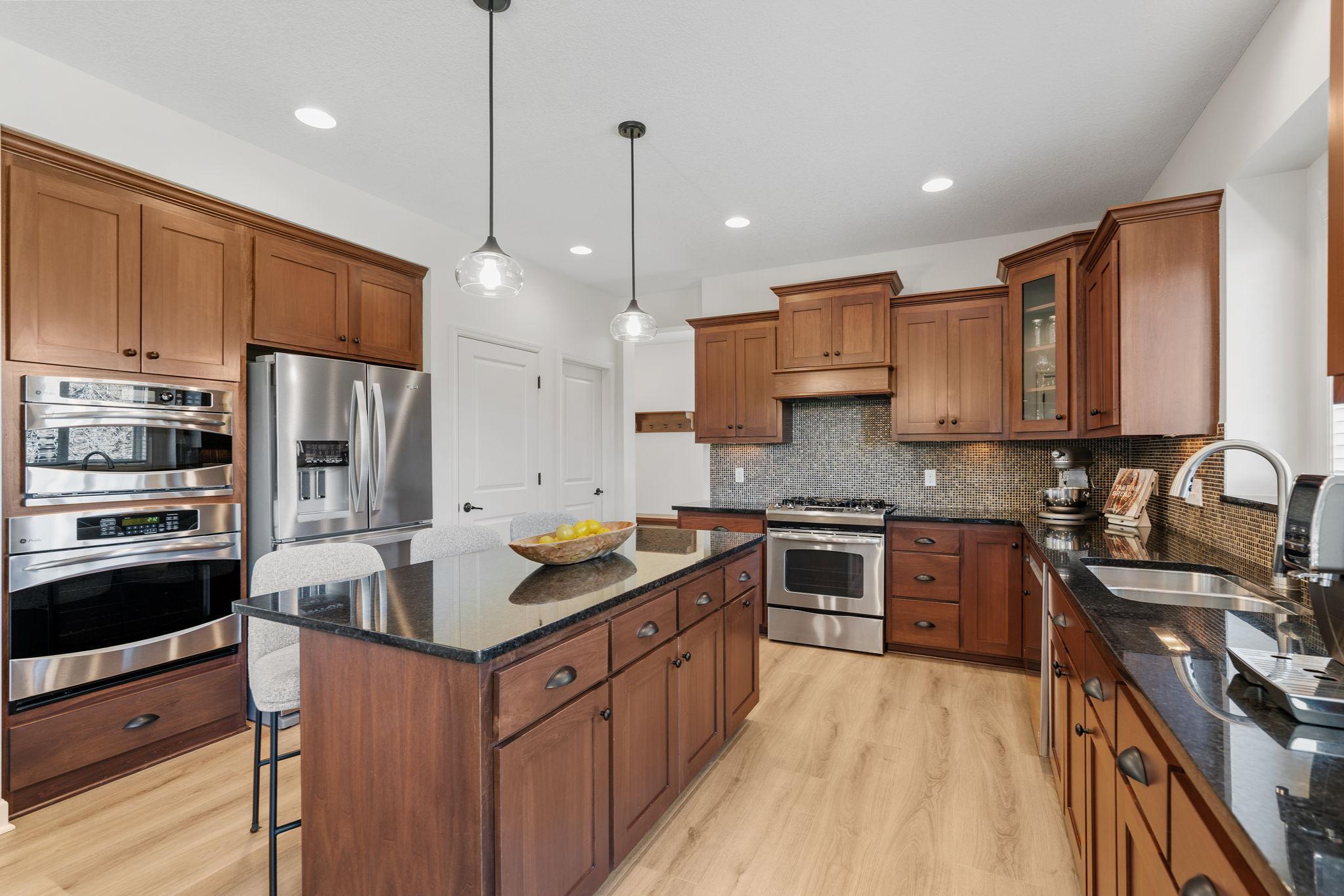 Gourmet Kitchen w/ large center island, granite counters, tons of cabinetry, SS apps, hood + walk-in pantry