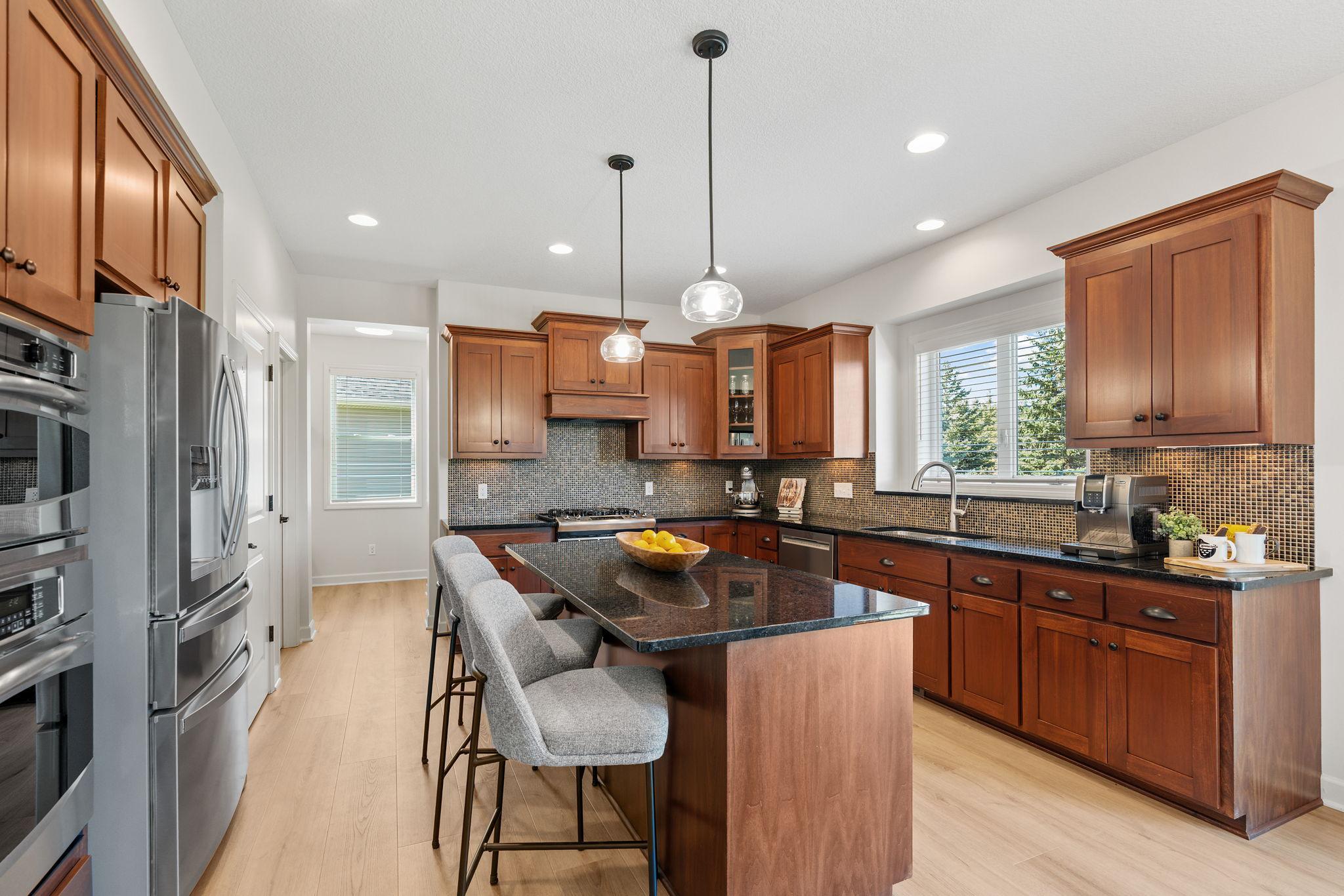 Gourmet Kitchen w/ large center island, granite counters, tons of cabinetry, SS apps, hood + walk-in pantry