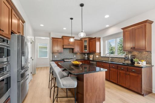 Gourmet Kitchen w/ large center island, granite counters, tons of cabinetry, SS apps, hood + walk-in pantry