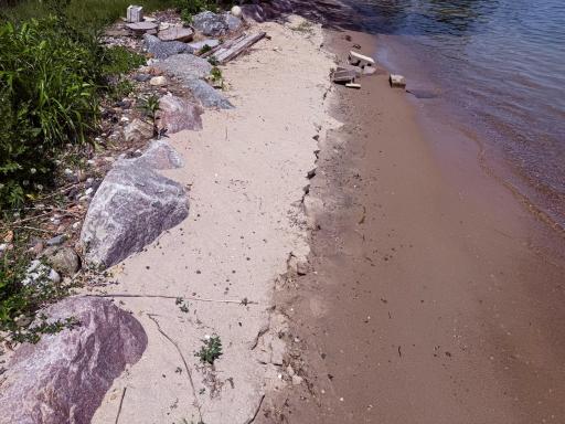 Sandy shoreline with large rip rap boulders
